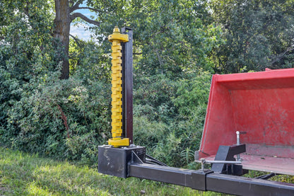 Bucket Mount Limb Cutter with its yellow cutting rotor upright beside a red tractor and bucket.