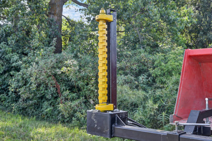 Closer view of the Bucket Mount Limb Cutter’s vertical yellow rotor beside a red tractor.