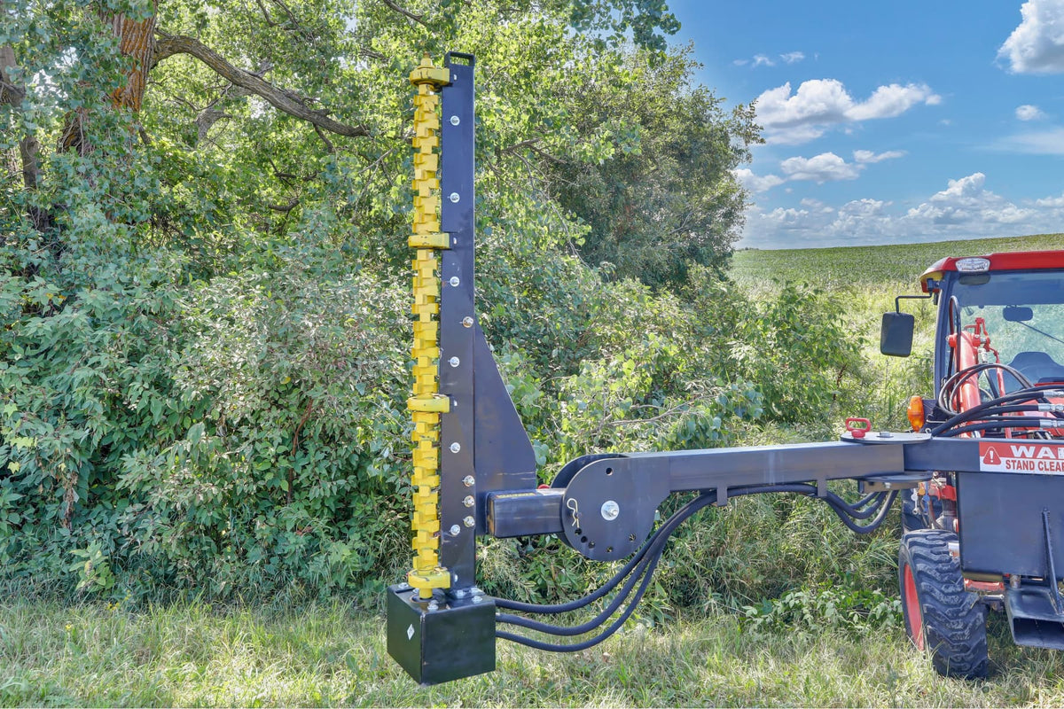 Quick Attach Compact Limb Cutter extended from a red tractor beside dense brush, showing its vertical yellow cutting rotor and hydraulic hoses.