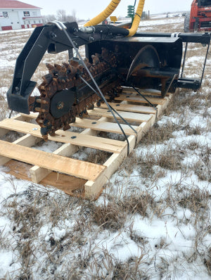 Mechanical claw attached to a vehicle over a wooden pallet with a snowy ground background