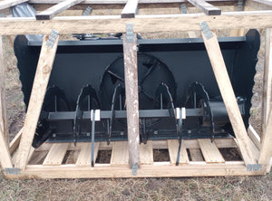 A black quick attach snowblower attachment, sitting on a wooden frame structure outdoors.
