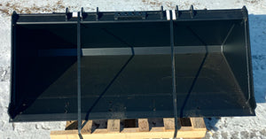 A black skid steer loader bucket placed on a wooden pallet, outdoors.