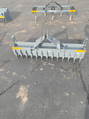 Gray agricultural implement with yellow accents on a cracked asphalt surface