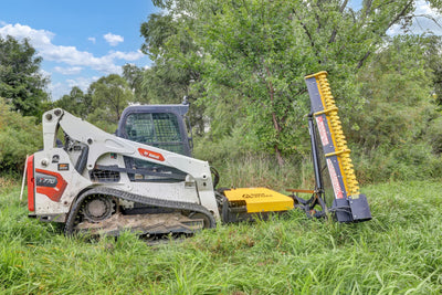 Side view of a skid steer with the Limb Cutter 6 attachment raised beside overgrown vegetation.
