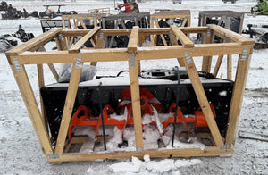 Snowblower in a wooden crate on a snowy ground