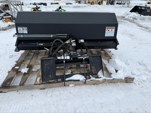 Large black piece of equipment on a wooden pallet in a snowy outdoor setting