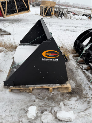 Black agricultural implement on a wooden pallet in a snowy outdoor setting