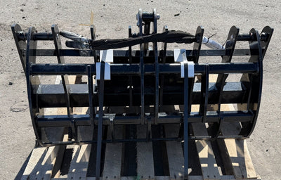 Black metal grapple attachment on a wooden pallet against a concrete floor.