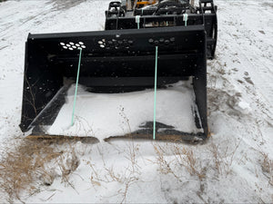 Large black snow plow attached to a vehicle on a snowy road