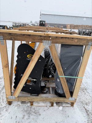 Person using a snow blower inside a wooden shelter in a snowy outdoor setting