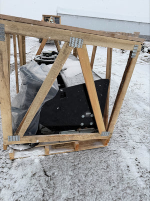Large black object inside a wooden frame on a snowy ground