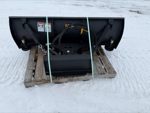 Black snow plow on a wooden pallet in the snow