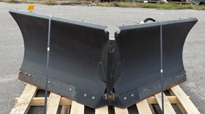 Large black metal snow plow on a wooden pallet outdoors.