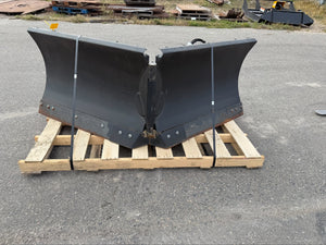 Large black metal snow plow on a wooden pallet outdoors.