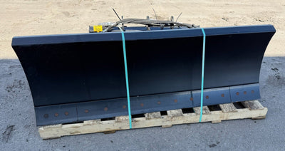 Large black snow plow on a wooden pallet outdoors